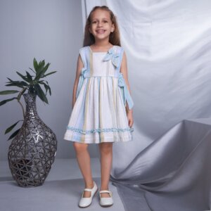 A smiling girl in blue lurex embroidered bow dress, posing straight