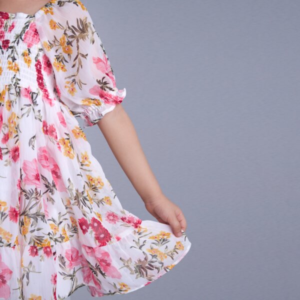 Closeup of an ivory floral printed elasticated dress with hem ruffle