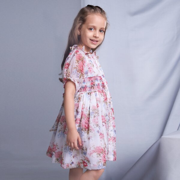 Side pose of a girl wearing an ivory floral printed smock dress