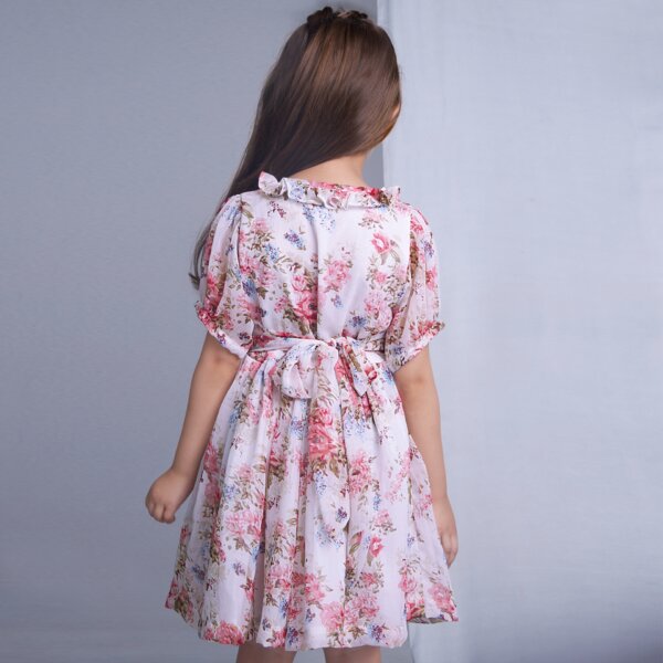 Back view of a girl in an ivory floral smock dress with tie up sash