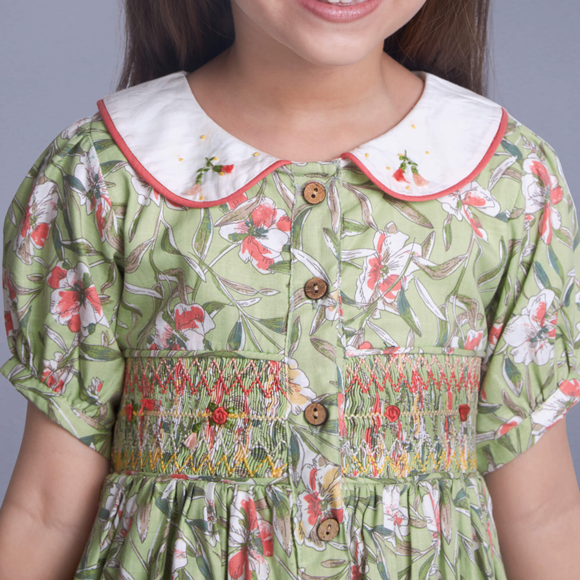 Close up of a girl wearing green floral embroidered smock dress