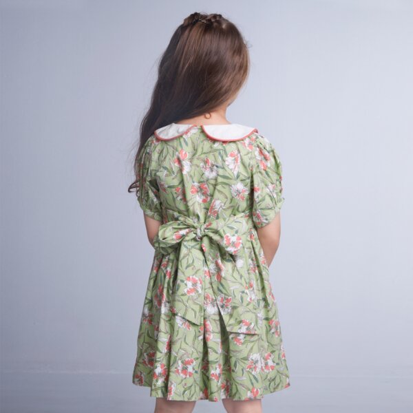 Back view of a girl in green floral smock dress with tie up sash at the back