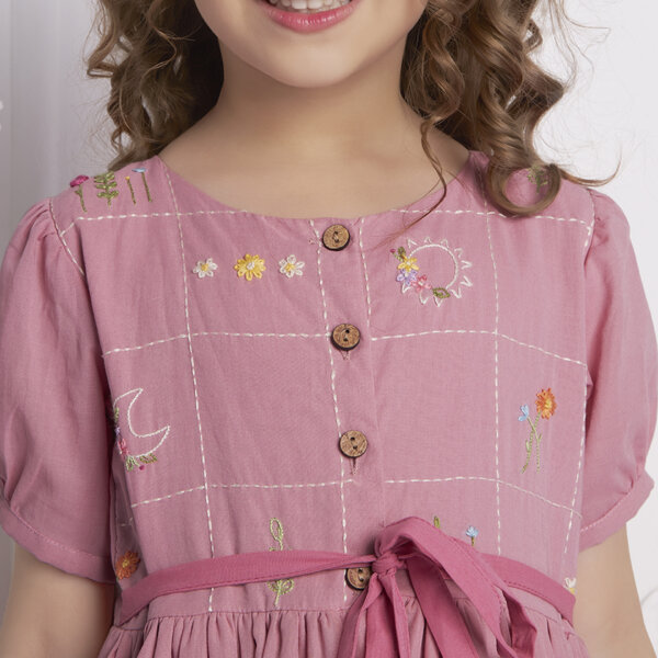 Close-up shot showcasing hand embroidery, tie-up sash in the front, fastened by wood buttons on a pink ombre dress