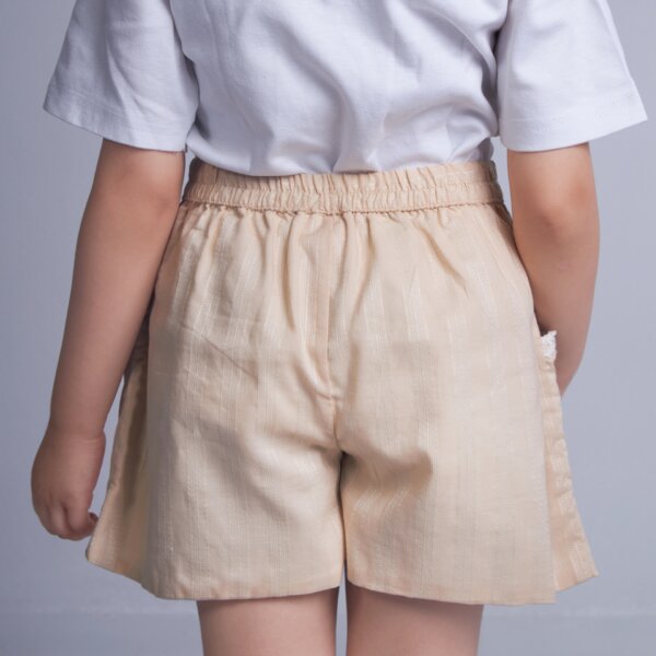 Back view of a girl wearing tan embroidered shorts