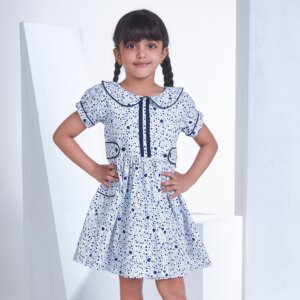 With hands on hips, a girl stands in white floral printed collared dress with adjustable side tabs