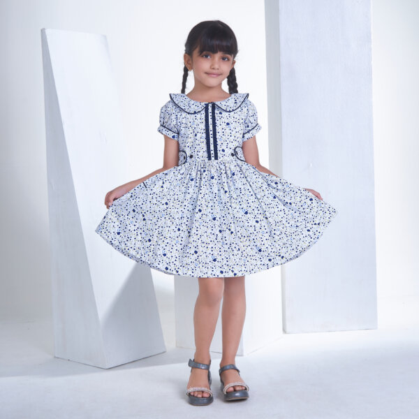 Posing gracefully, a pretty girl showcases a white floral printed collared dress with an adjustable belt at the waist