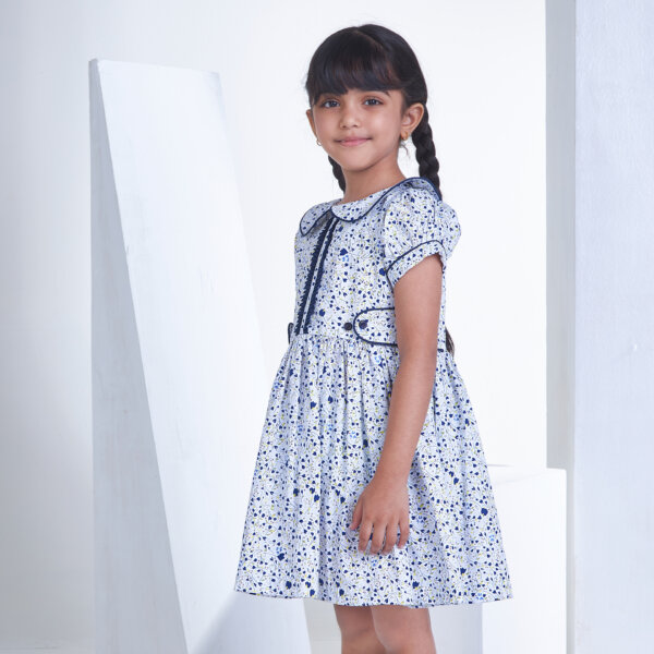 Side pose of a girl in white floral printed collared dress with adjustable side tabs