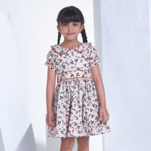 A little girl in white floral printed collared dress with adjustable side tabs