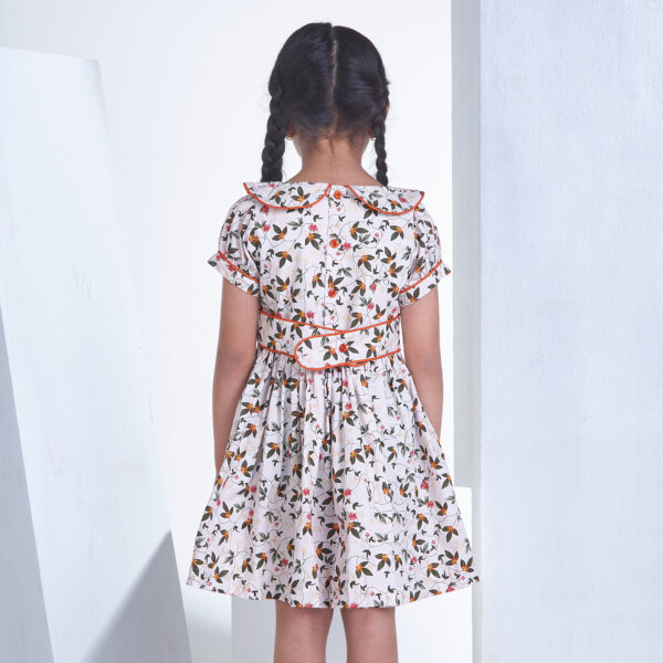 A girl seen from behind dressed in ivory floral printed collared dress with an adjustable belt