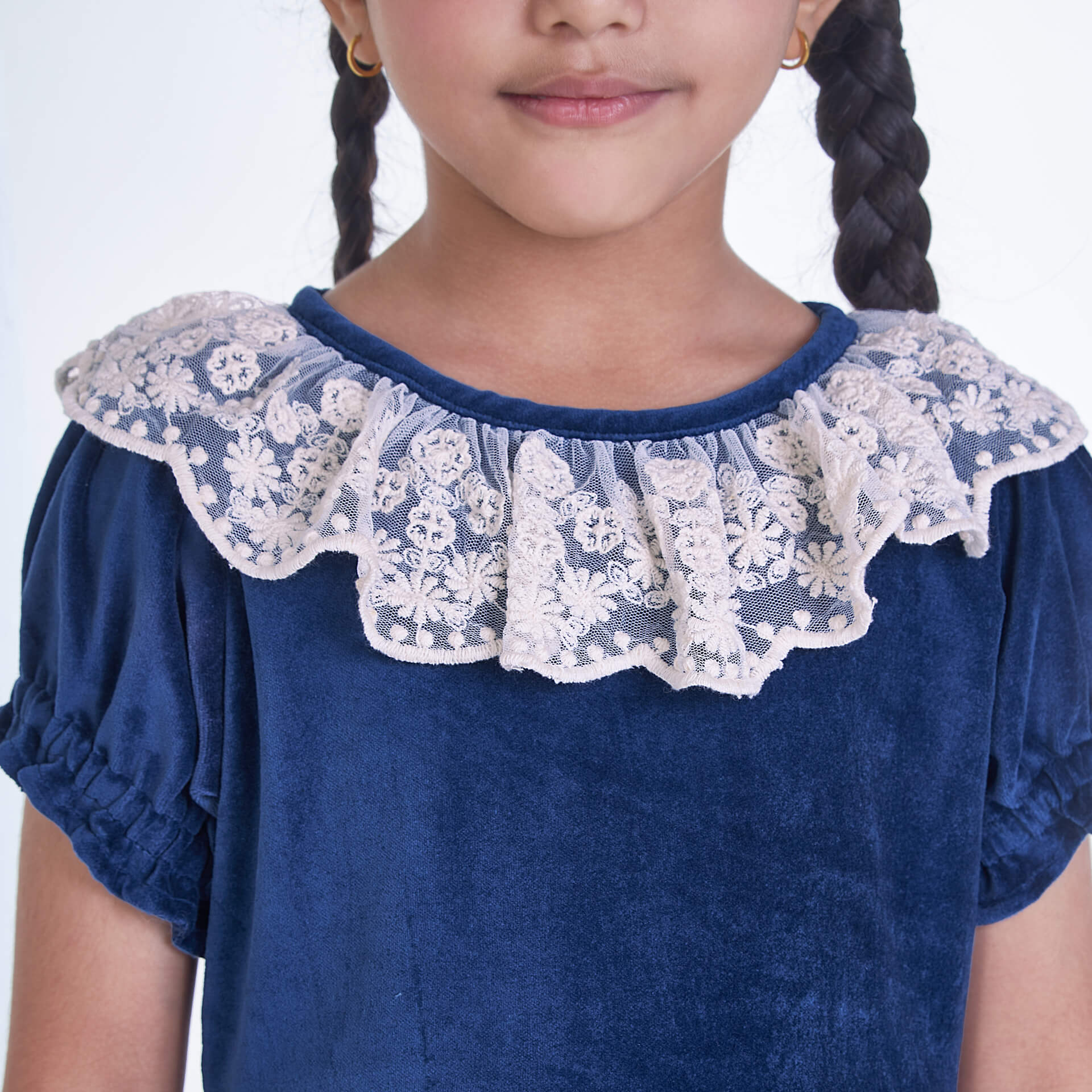 Closeup shot of ruffled neckline with lace trims, in a navy velvet dress