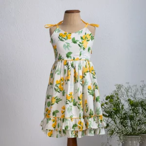 Mannequin in kids white dress with yellow and green floral prints, adjustable straps, and double ruffled hem