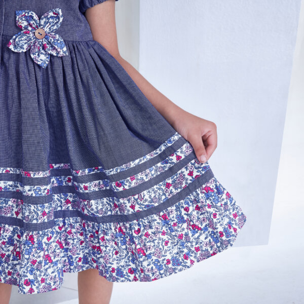 Closeup of the flower applique and details in the skirt of a navy flower applique dress