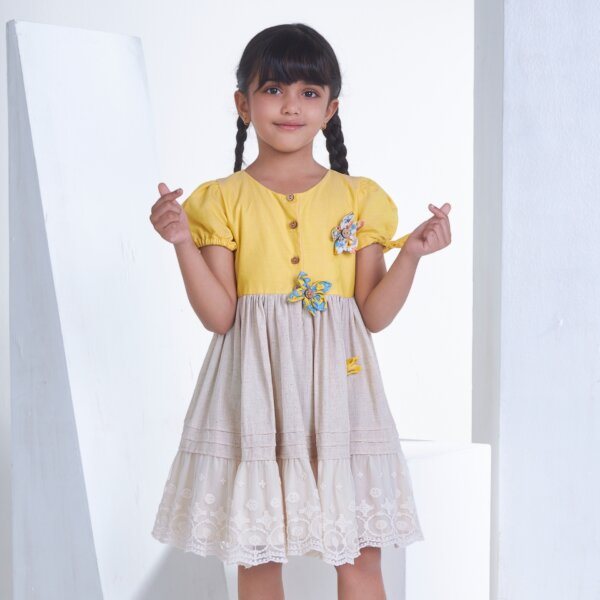 A little girl in yellow flower applique dress adorned with lace