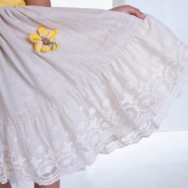 Closeup of the flower appliques and details in the skirt of a yellow cotton dress