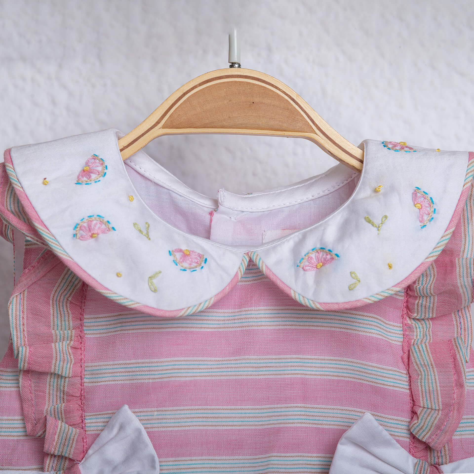Close-up of hand embroidery detail on pink striped peter pan collared baby girl onesie from Soleilclo.