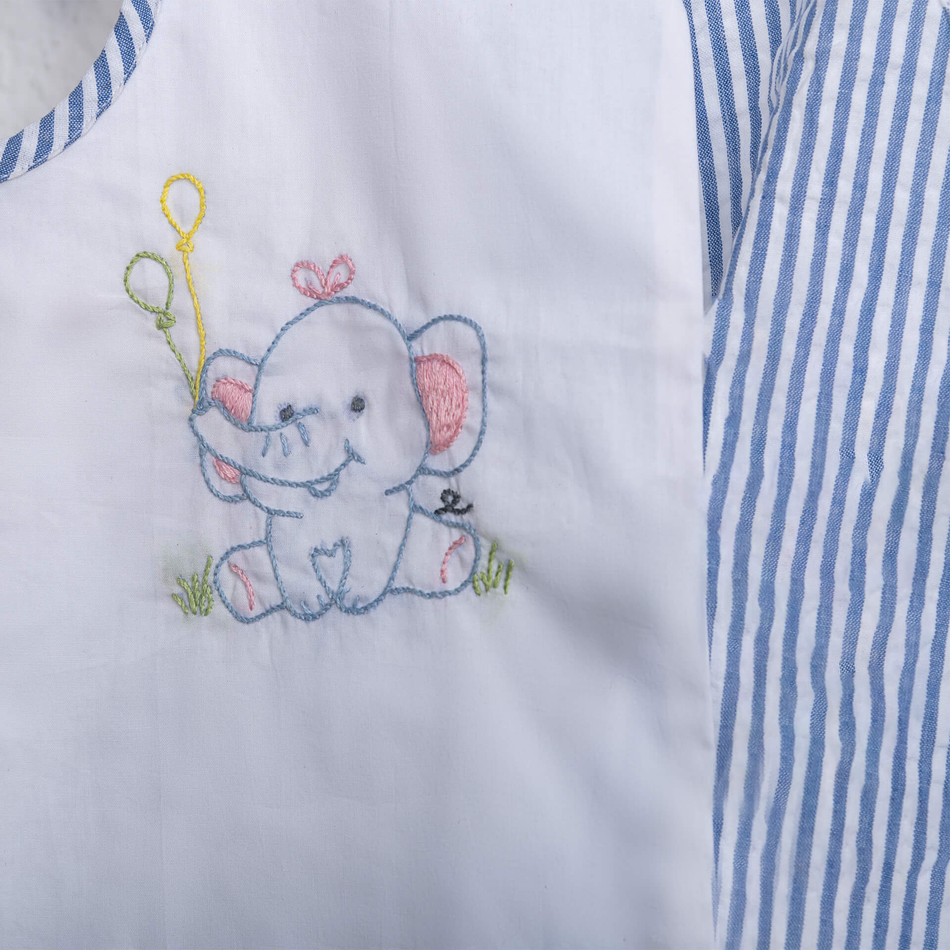 Close-up of hand-embroidered elephant on a white jabla set for baby girl by Soleilclo